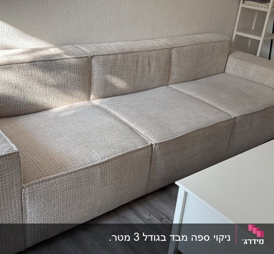ספה בהירה ליד שולחן לבן בחדר מואר